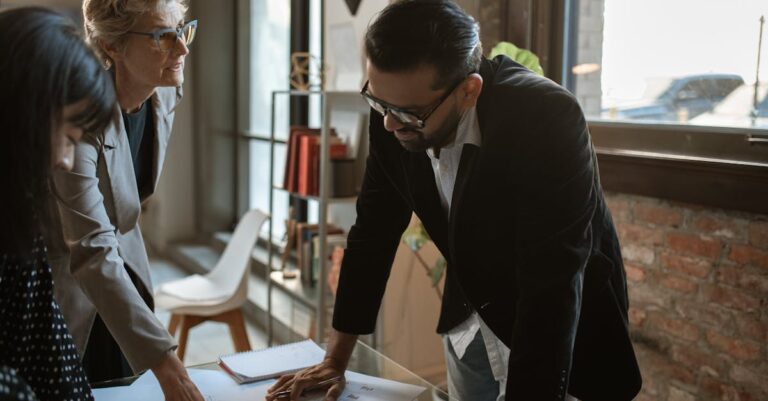 Três profissionais interagindo em uma reunião em escritório contemporâneo