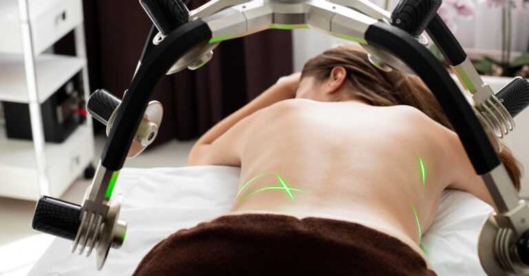 Mulher deitada em uma mesa de tratamento recebendo terapia a laser nas costas.